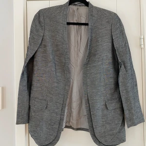 Svart och beige kavaj i linne och viskos från Tiger of Sweden i strl 36 - Svart och beige kavaj i linne och viskos från Tiger of Sweden i strl 36. Modell Zurie  Sparsamt använd och i fint begagnat skick.  Mått Över bröstet: ca 47 cm Längd från axeln och ner: ca 73 cm  55% linne och 45% viskos