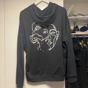 Svart hoodie - Svart hoodie med jätte snyggt tryck på ryggen från SHEIN. Endast använd enstaka gånger på gymmet. Ganska tunt material så den sitter slappt