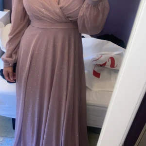 Fin långärmad rosa klänning med glitter - Fin långärmad rosa klänning med glitter, strl M, passar även S, köpt på LS butiken i Göteborg använd en gång på ett bröllop, köpt för 2000 säljer 1000