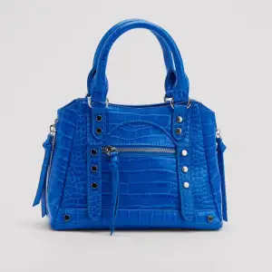 Säljer denna blåa handväska från NAKD ( följer med längre axelband )🌸 Väl använd men inga defekter alls, säljs inte längre på hemsidan💞
