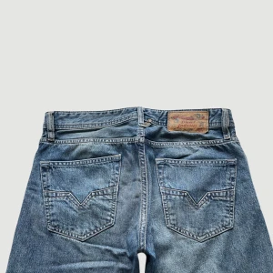 Diesel - Raka Jeans - Storlek 29 - VARAN KAN KÖPAS DIREKT PÅ VÅR HEMSIDA, ettmarke.se MÄRKE: Diesel Industry. MODELL: Reg - Straight. FÄRG: Blå. STORLEK: W29 L30. MIDJA RAKT ÖVER: 41 cm. MIDJEHÖJD: 25 cm. TOTALLÄNGD (FRÅN MIDJAN): 103 cm. BENLÄNGD (FRÅN INNELÅRET): 78 cm. 