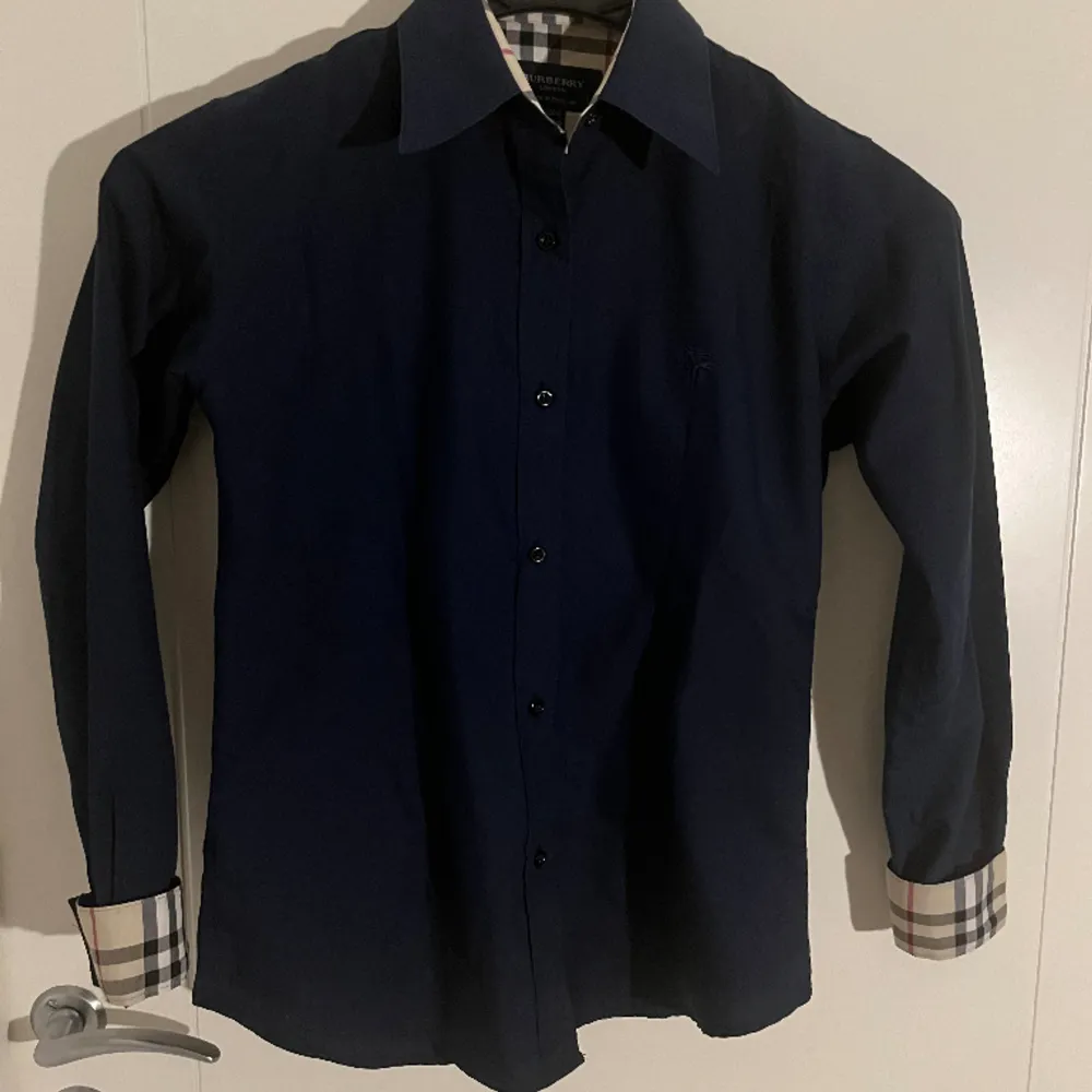En stilig Burberry skjorta i mörkblått som säljs pga liten storlek. Använd endast ett fåtal ggr. Taggen säger S men passar även s/xs herr och M/S/XS för dam. Kan mötas upp i karlstad.. Skjortor.