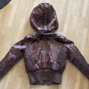 Baby phat jacka - Jättefin vintage jacka, perfekt nu när det börjar bli lite varmare! Använd men fortfarande i bra skick. Strlk M men ganska liten! Jag är runt 158 på bilden, den sitter lite croppad! Luvan är avtagbar.