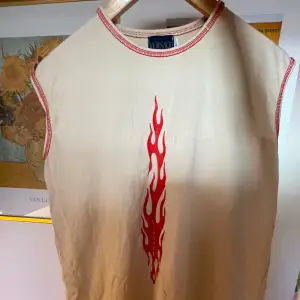 Beiget Versace linne i beige med röd flamma fram och röda sömmar. Unisex. Storlek S-L