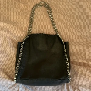 Tiamo väska - Jättefin liknande stella mccartney väska. Bra skick, förutom att den har gått sönder lite uppe men lagat med säkerhetsnål (se bild). Skriv om ni har några funderingar eller vill ha fler bilder🩷🩷