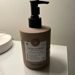 Maria Nila hårmask brun   - helt oöppnad flaska av en hårmask med färg. Man ser på andra bilden att ett skydd sitter på och alltså är förpackningen inte öppnad. Den har inte kommit till användning. Nypris 300 kr 