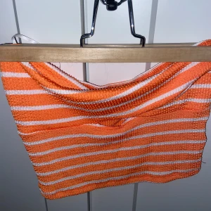 Randig orange och vit tubtopp - En randig tubtopp i orange och vitt. Toppen är ärmlös och har en tight passform med en twist i tyget över bysten💕använd ett fåtal gånger. 