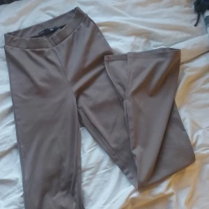 Bruna tajts - Storlek S, högmidjade, flare. 16 cm lång slits längst ner på insidan av byxbenen. 