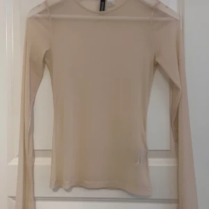Beige långärmad tröja från H&M - En guldig långärmad tröja från H&M. Tröjan är enkel och stilren med en tight passform. Jättefin till fest och liknar intimissimi tröjorna lite