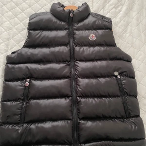 Moncler Väst - Ej äkta. Fick denna i present för ett tag sedan. Använd 1 gång, men passar mig inte bra i storlek.   Inga tecken på användning. Storlek L.  Hör av dig om du har frågor!