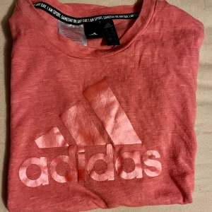 Adidas t-shirt - Adidas tisha. Skönt material, antingen som träningsteöja eller bara casual. Rosa i färgen med uppkavlade ärmslut.