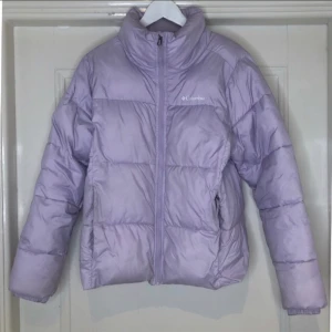Columbia Puffer Jacka - Ljus lila Columbia jacka i storlek M. Sparsamt använd vid ett fåtal tillfällen.   Skick: Säljs i befintligt skick.  Jag anser att skicket är 9/10. Har ej testat tvätta.   Färg, ljus lila  Nypris: 860 köpt på Asos 2022