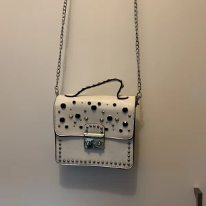 Väska - Vit liten väska med strass på. På baksidan är den lite missfärgad då den legat mot en annan svart väska. 