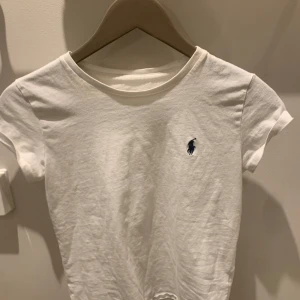 Ralph Lauren tröja - En fin Ralph Lauren t-shirt. Tröjan är vit med ett mörkblått märke på bröstet i storlek XS. Inga slitningar eller hål förutom borttvättad etikett, se bild 3. Annars väldigt stilren och casual t-shirt💞 man kan pruta, SÄLJS IDAG SÅ PASSA PÅ