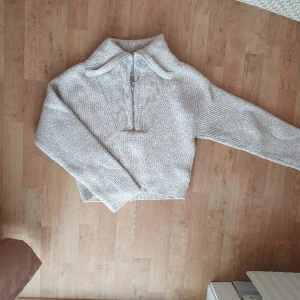 Beige grovstickad tröja polo vringad - Mysig grovstickad tröja i beige/vitmelerat garn från H&M. Polokrage eller V-ringad beroende på styling. Storlek XS men passar fint på mig som har storlek S. Fint skick, inga defekter/noppror eller annat slitage vad jag kan hitta!
