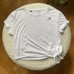 Gymshark t-shirt med knytning i sidan. Lappen med storlek är sliten så kan inte se storleken, men är 99% säker på XS. Lite nopprig.