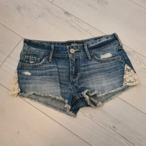 Lågmidjade jeansshorts - Så fina lågmidjade jeansshorts med lite spetsliknande detaljer på sidorna, märket är Hollister💓 Midjemått= 36 cm Hör av dig om du har övriga frågor! 
