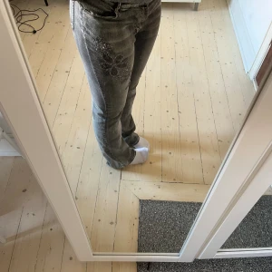 Gråa jeans med blommor på - Otroligt fina low waist jeans med glittriga blommor både fram och bak. Även bootcut! ❤️❤️