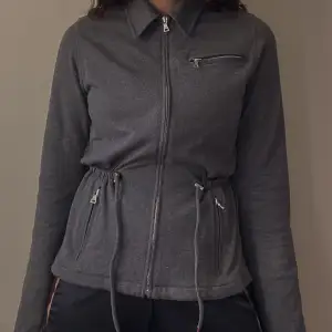 Beautiful Vintage Prada Milano Cotton Knit Zip Sweater Jacket in Grey.  Silver colored metal hardware with embossed “Prada Milano”.  1 Top Zip and 2 Side Zip Pockets + a  drawstring feature for an adjustable waist. Some yellowing around shoulders 