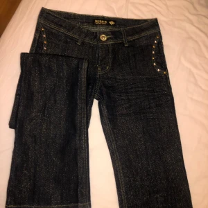 Guldglittrande lowwaist jeans - Lowwaist marinblå bootcut jeans med guldglittrigt tyg
