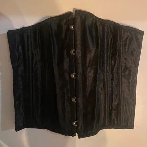 Korsett - Svart korsett med boning och snörning i XS. Midja till under byst.