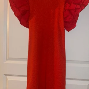 Röd klänning med volang-ärmar från Zara i nyskick! - Endast använd 1 ggn. Nyskick. Står att det är en L men den är mer en M enligt mig. Mindre L i sådana fall.