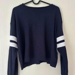 Snygg Hollister-tröja - Snygg, marinblå, något croppad tröja från Hollister med snygg design på ärmarna.