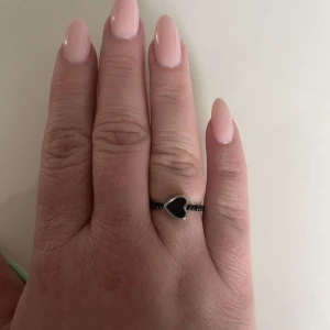 Egengjord pärlring - Egengjord pärlring med svarta små pärlor. Ringen har en hjärtformad svart pärla med silverram. 