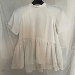 Vit topp - Jättesöt och trendig topp i peplum modell med öppen rygg och knytband. Dessvärre för tight över brösten (B-kupa) så säljer. 
