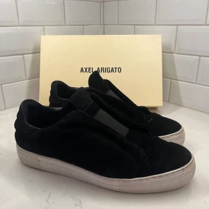 Axel Arigato Laceless - Ett par använda Arigato Laceless som är sjukt populära! Förutom att Arigato tagen i guld är sliten så syns det även på sulorna att dem är slitna och därav priset! Nypris 2500 och Orginalbox ingår! Priset är diskuterbart vid en smidig affär😊