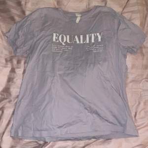 Superfin ljuslila T-shirt med tryck ”Equality” + definition (tryck) Nyskick (använd 1 gång) Säljer pga att den inte används Svagt märkt med initialer på lapp inuti