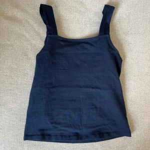 Topp med knytband  - Marinblå topp med knytband vid axlarna. Knytbanden går att justera och knyta om precis som man vill ha dem! 