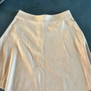 Fin ljusrosa kjol - Materialet ser lite ut som mocka. Fin puderrosa färg   Jättefint skick 