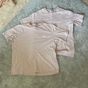 Beige t-shirt från H&M Divided - Två rosa t-shirtar från H&M Divided med texten 'LOVE' tryckt på framsidan. T-shirtarna har korta ärmar och en rund halsringning.