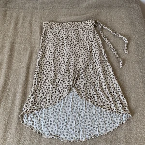Leopardmönstrad kjol från KappAhl - En beige leopardmönstrad kjol från KappAhl. Kjolen har en omlott-design med knytband i midjan och är tillverkad i ett lätt och luftigt material.