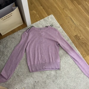 Rosa stickad kofta  - Stickad kofta i skolan en jätte fin rosa/lila färg. Använd 1 gång känns som ny!