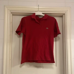 Lacoste - Snygg röd Lacoste pike! Inga defekter alls. Storlek XXL i barn men passar XS/S Skriv pm vid frågor!