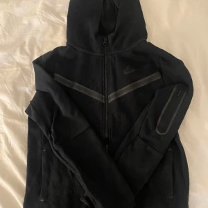 Svart Nike tech - En svart Nike tech fleece i bra skick. Den har inga stora tecken på användning. Den är i barnstolen men passar som Xxs och xs. Nypris 950