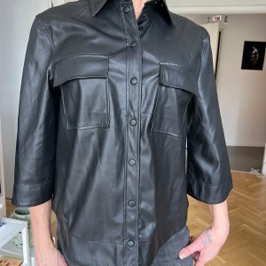 Skjorta - Nyskick, skinnimitation med tryckknappar och 3/4 lång arm