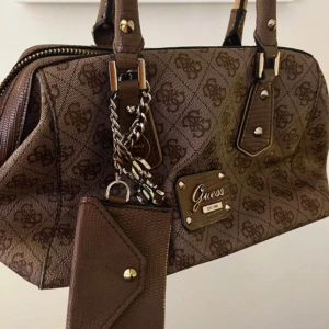 Guess väska  - Guess väska i bra skick! Den har få defekter som man ser på bilden men den går att använda jättebra! 