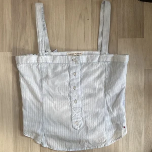 Tommy Hilfiger topp -  Jättefin Tommy Hilfiger ljusblå topp med vita ränder. Fina detaljer och knappar på framsidan. Endast använd 1 gång, så den är som ny!