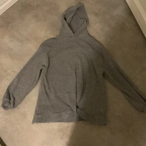 Grå hoodie - Säljer en grå hoodie från Zara. Längst nere på tröjan är det ett litet knyte som man kan se på bilderna. Tröjan är även ribbad. Tröjan har inte använts någon gång 