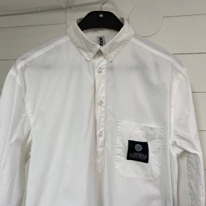 Dope Skjorta - Lång tuff skjorta med fina detaljer som knappar på sidorna. Använd ett fåtal gånger så i fint skick. Strl. XS. Frakt tillkommer