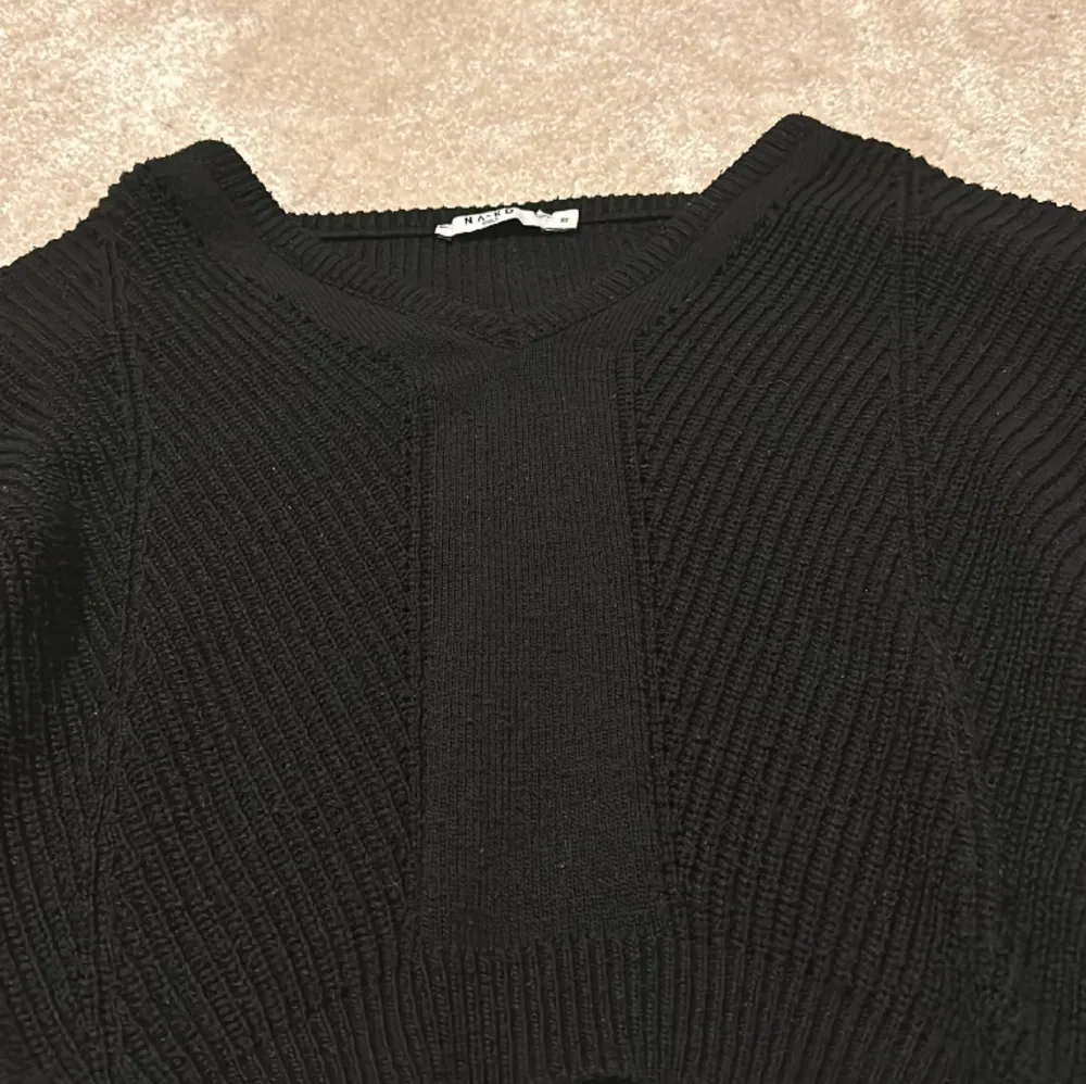 Säljer denna svarta ribbstickade tröjan från nakd som är använd ett fåtal gånger! Har fin detalj framtil och är v-ringad🩷. Stickat.