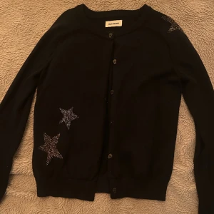 Zadig & Voltaire kofta - Säljer min svarta kofta med glittriga stjärnor från Zadig & Voltaire. Endast använd fåtals gånger och har inga defekter och är i nyskick🥰