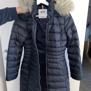 Tommy Hilfiger jacka - Tommy Hilfiger lagom lång jacka i jättebra kondition, det finns inga revor eller fläckar. Bara använt ett par gånger och funkar perfekt för vintern. 