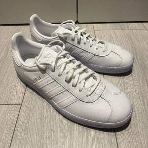 Säljer dessa ”Adidas Gazelle Originals” (White) i storlek 44 (US 10). Skorna är helt oanvända och köptes från ”adidas.com” för 1250 kr. Om ni är intresserade av att köpa skorna eller vill ha mer information så får ni gärna höra av er!