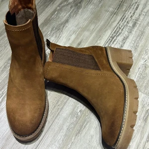 Platåstövletter  - Platåstövlar från Tamaris aldrig använd, i fin cognac färg och snygg modell på plattorna. Bekväma och matchar med mycket kläder. 