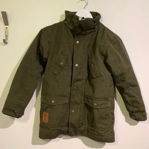 WA barnjacka i oliv - Använd barnjacka utan defekter. Den är fodrad och passar barn i ungefär 10 års åldern. Pris kan diskuteras, köparen står för fraktkostnaden. 