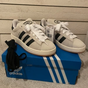 Adidas Orginals Campus 00s - Säljer mina helt nya och oanvända Campus 00s i färgen "CRYSTAL WHITE CORE BLACK" eftersom jag behöll en mindre storlek och inte kan skicka tillbaka dessa. Köpta för 1899 kr men säljer för 1600 kr. Köparen står för frakten!